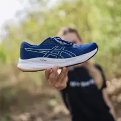 Dłoń trzymająca niebieski but Asics z białym logo. Idealna rozmiarówka Asics dla biegaczy.
