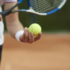 Tenisista trzyma piłkę do serwisu, gotowy do gry. Tie break w tenisie gra się do 7 punktów.