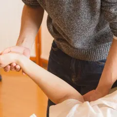 Fizjoterapeuta delikatnie masuje przedramię pacjenta, pokazując, jak leczyć łokieć tenisisty.