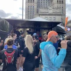 Grupa biegaczy przed budynkiem, dyskutują, czy można biegać codziennie. Na koszulkach napis "Run your way".
