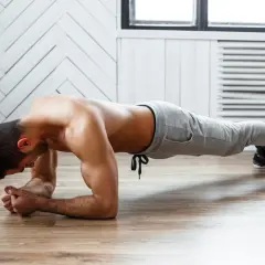 Mężczyzna wykonuje ćwiczenia na mięśnie głębokie brzucha w pozycji deski.