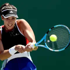 Garbine Muguruza z determinacją uderza piłkę rakietą podczas meczu tenisowego.