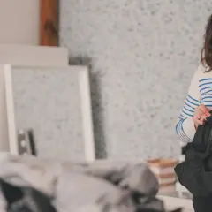 Kobieta w paski sprawdza metkę czarnej kurtki, przygotowując się do tego, jak prać spodnie narciarskie.