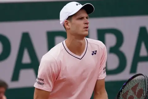 Hubert Hurkacz w różowej koszulce i białej czapce z logo Yonex, gotowy do gry na korcie.