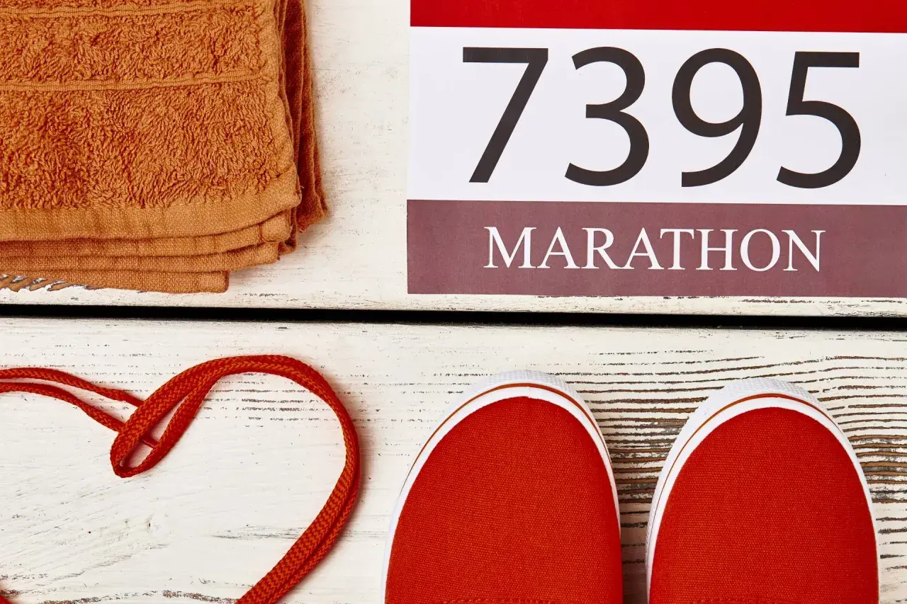 Pomarańczowy ręcznik, czerwone buty i numer startowy 7395 z napisem MARATON. Czas na maraton!