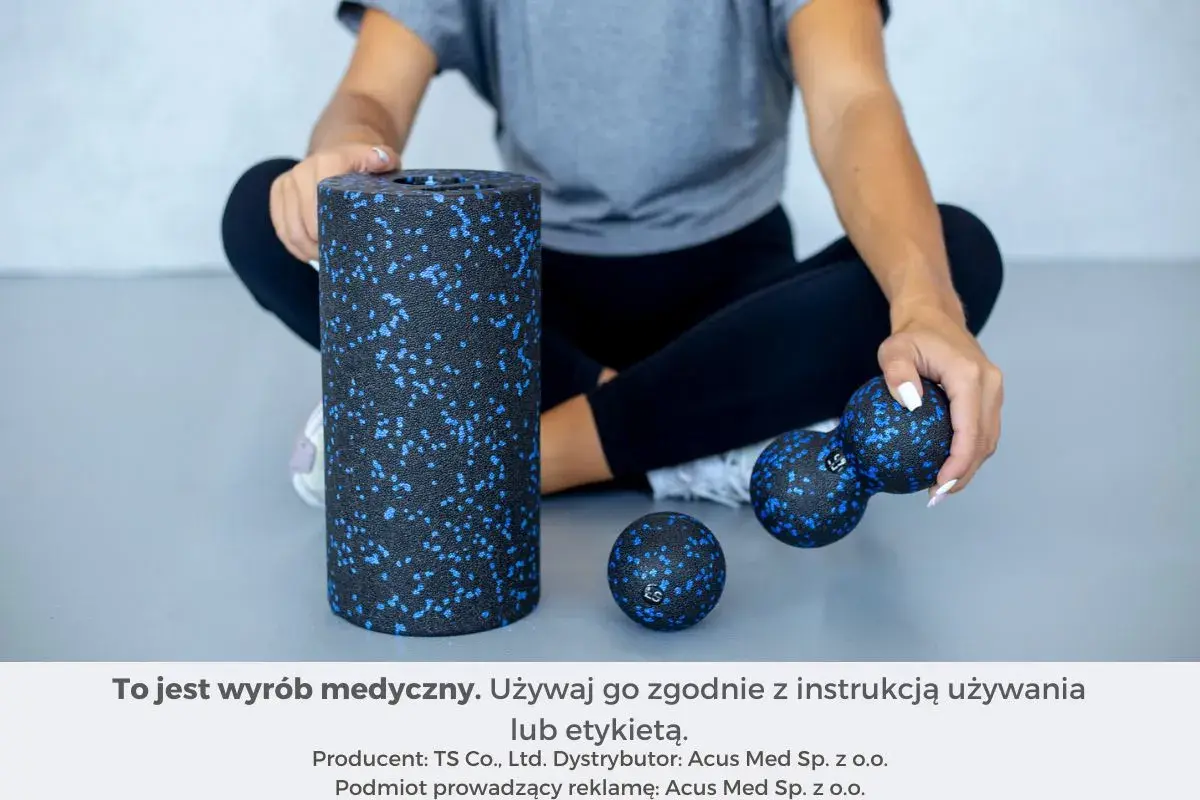 Kobieta siedzi obok wałka i piłek do rolowania mięśni.