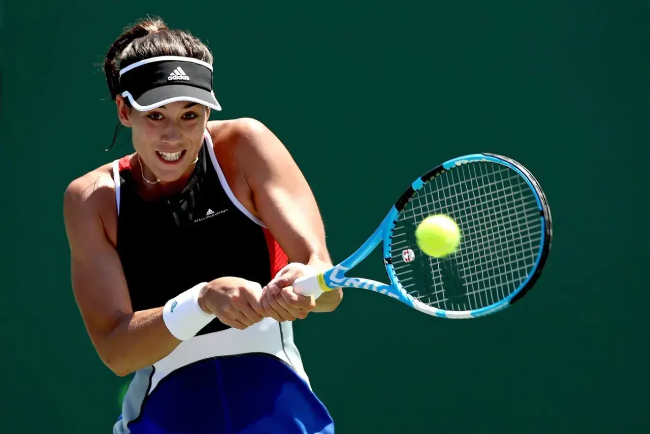 Garbine Muguruza z determinacją uderza piłkę rakietą podczas meczu tenisowego.