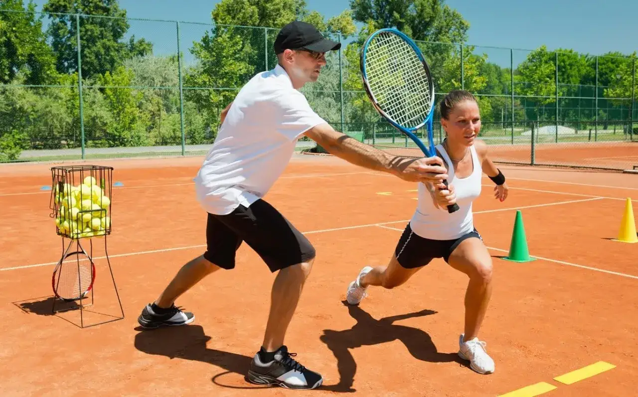 Trener pokazuje techniki gry w tenisa. Sprawdź, jaka jest lekcja tenisa cena i zacznij grać!