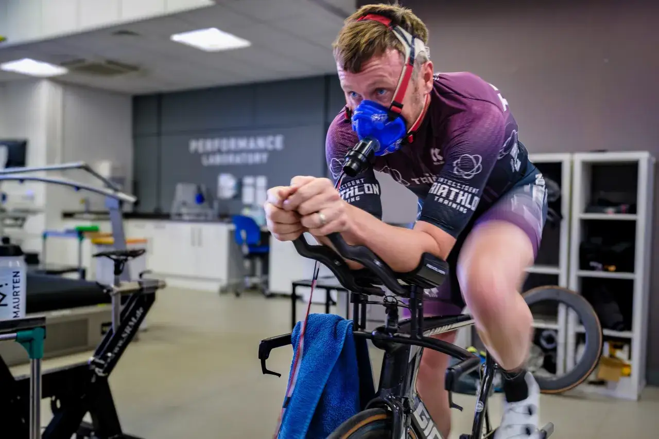 Zawodnik w masce mierzy swoje VO2 max podczas intensywnego treningu kolarskiego w laboratorium wydajności.