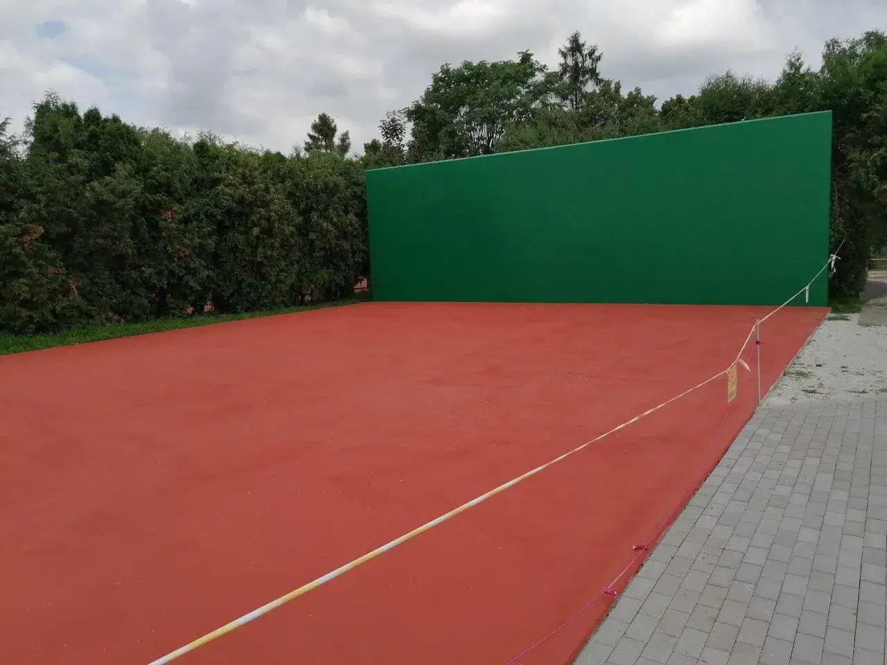 Boisko z czerwoną nawierzchnią i zieloną ścianką do odbijania piłki. Jak zrobić taką ściankę?