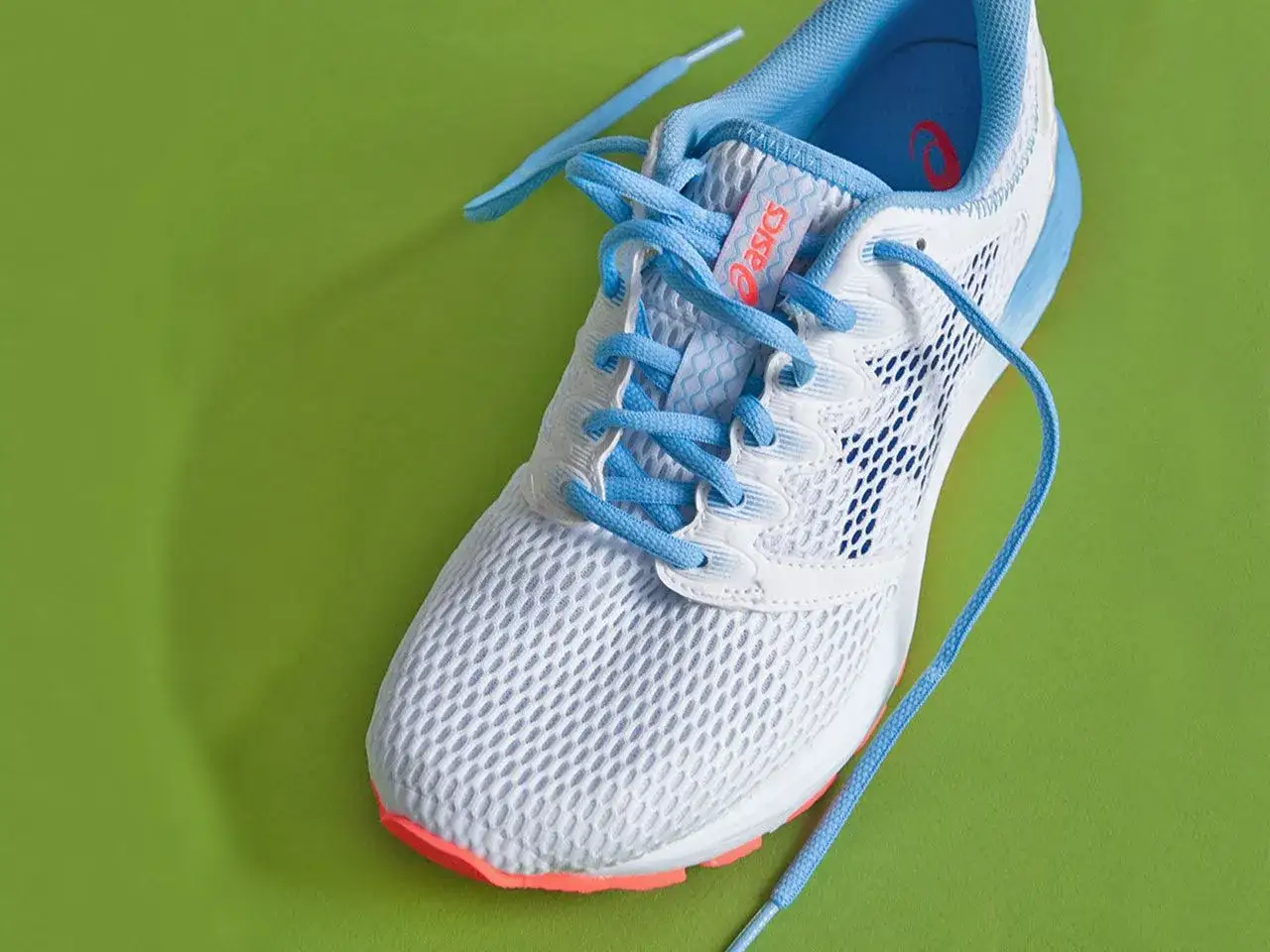 Białe buty do biegania Asics z niebieskimi sznurówkami. Dowiedz się, jak wiązać buty do biegania, by były idealnie dopasowane.