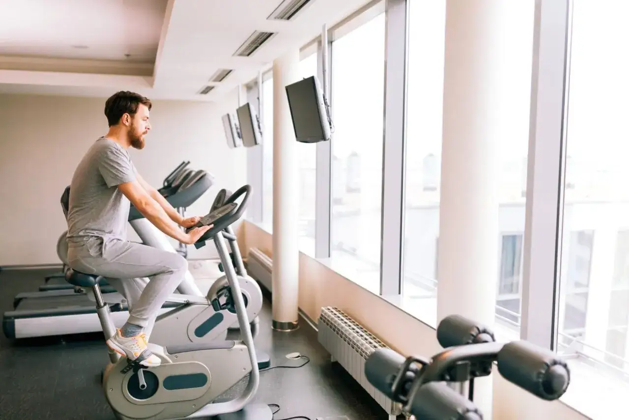 Mężczyzna ćwiczy na rowerze stacjonarnym, który może być dobrym wyborem, jeśli zastanawiasz się, jaki rower stacjonarny do rehabilitacji kolana wybrać.